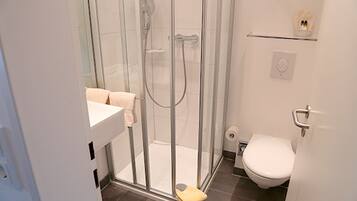 Ein modernes Badezimmer mit einer Glasdusche, einer Toilette und einem Waschbecken.