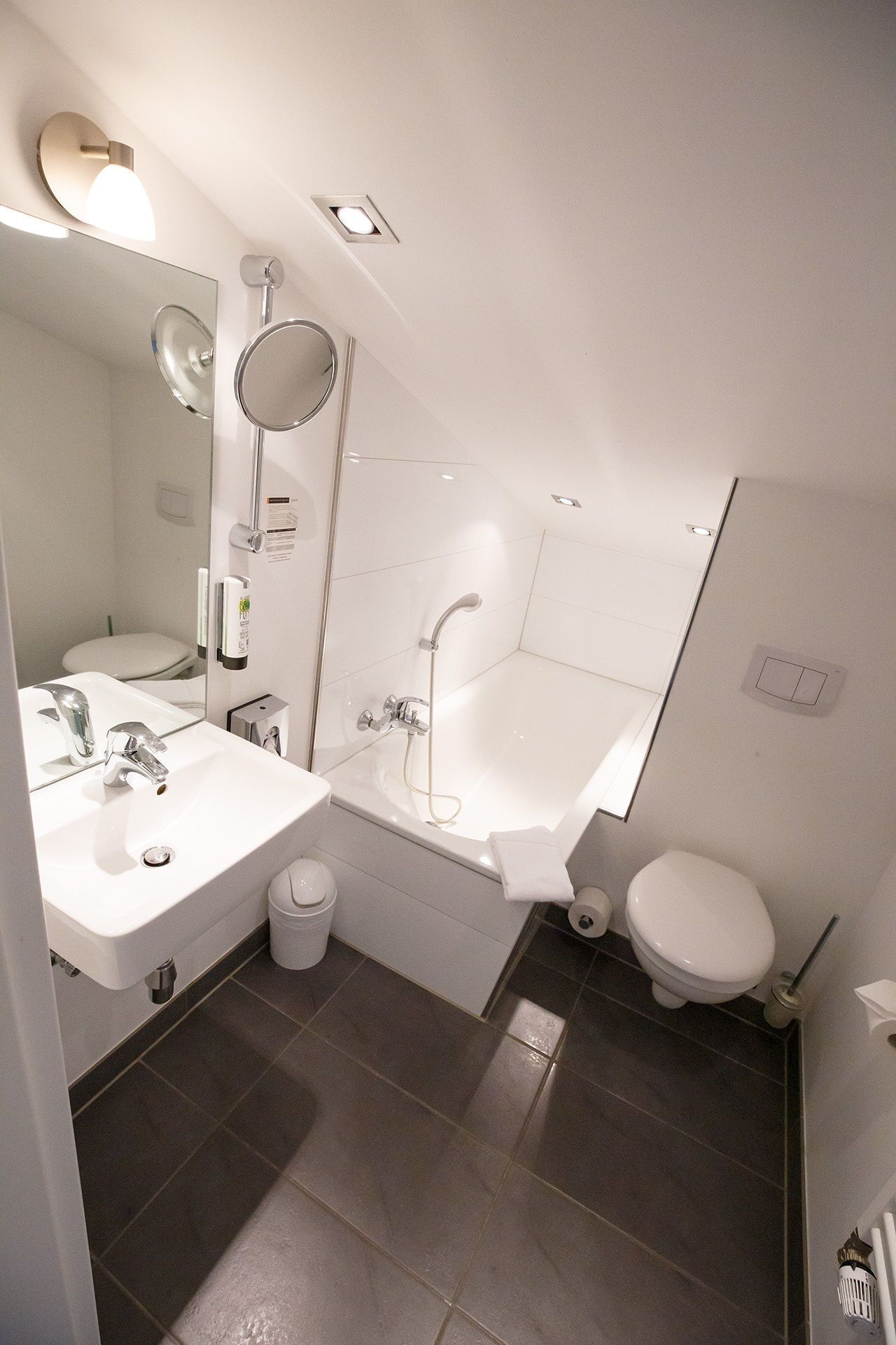 Ein modernes Badezimmer mit Waschbecken, Spiegel, Toilette und Badewanne.