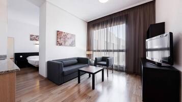 Une chambre d’hôtel moderne équipée d’un canapé, d’un fauteuil, d’une table basse et d’un téléviseur à écran plat.