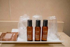Trois bouteilles de shampoing liquide sur un plateau blanc, avec un paquet de dosettes à côté.