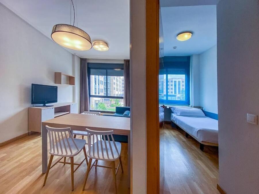 A modern apartment with a dining area, a TV, and a bed.