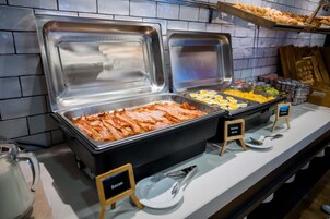 A buffet with various food items including bacon, eggs, and cheese.