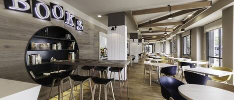 A modern library with bookshelves, tables, and chairs.