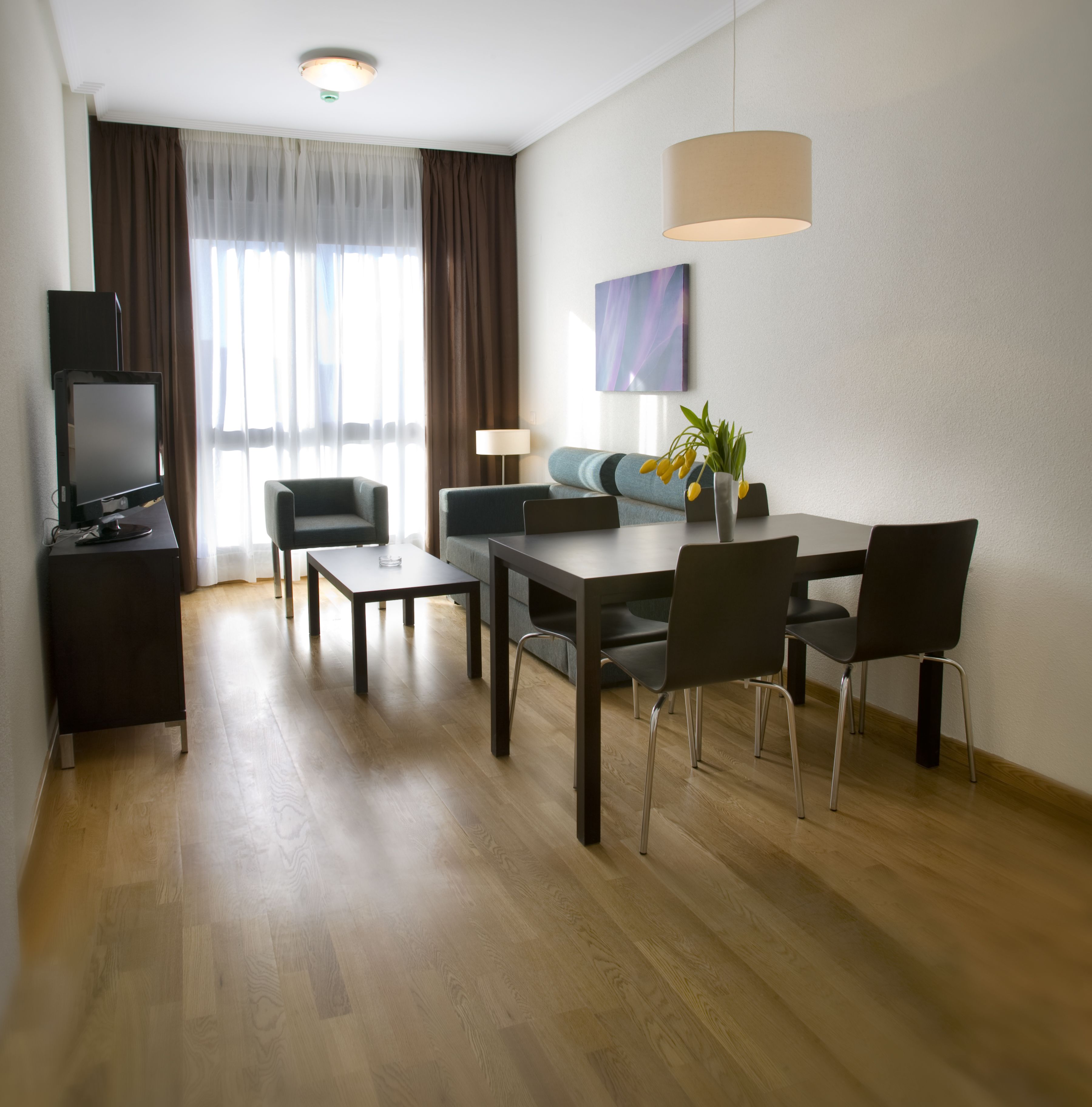 Een moderne hotelkamer met een eethoek, een televisie en een bank.