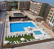 Ein Dachpool mit mehreren Schwimmbereichen, Liegestühlen und einer Kinderspielanlage.