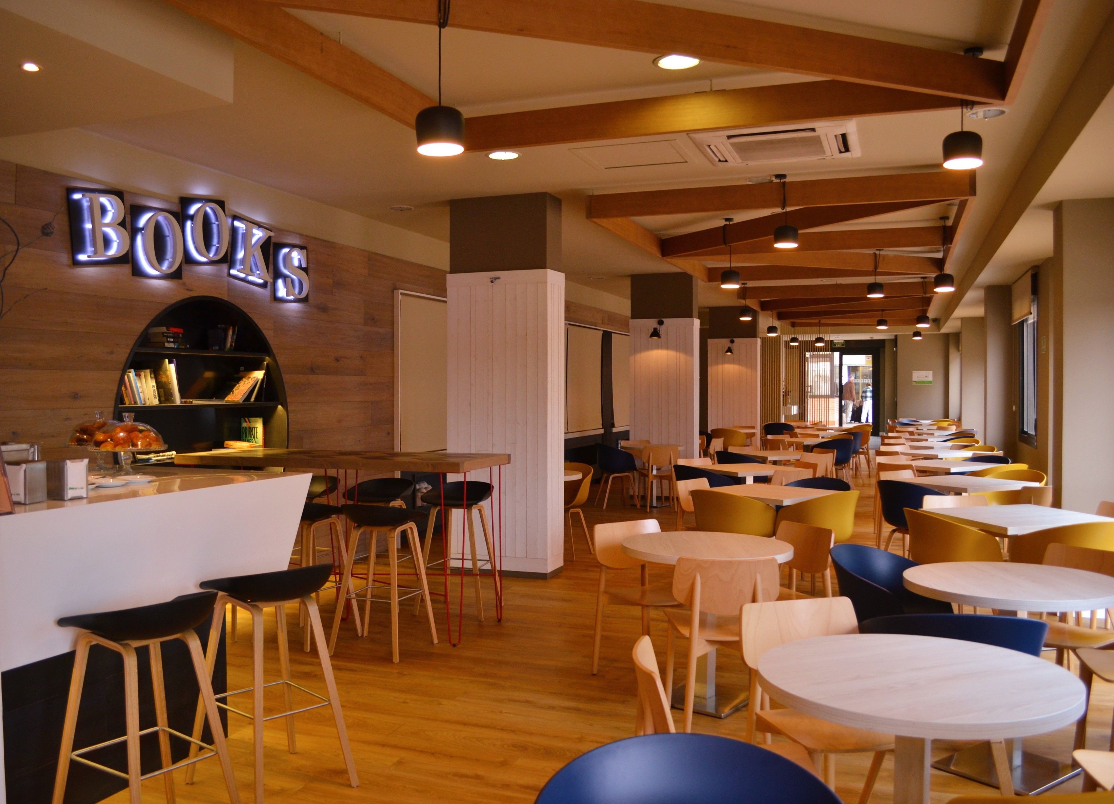 Un café moderno con detalles de madera, una barra y diversas opciones de asientos, incluidas mesas y sillas.