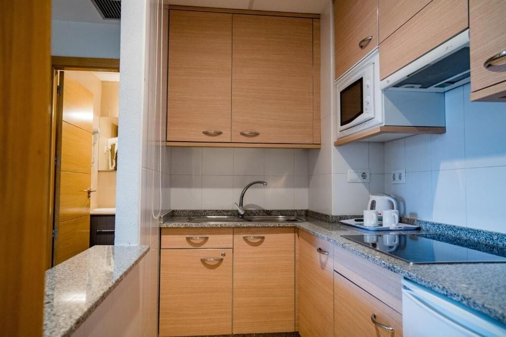 Una cocina con armarios de madera, encimera de granito, microondas y hervidor.