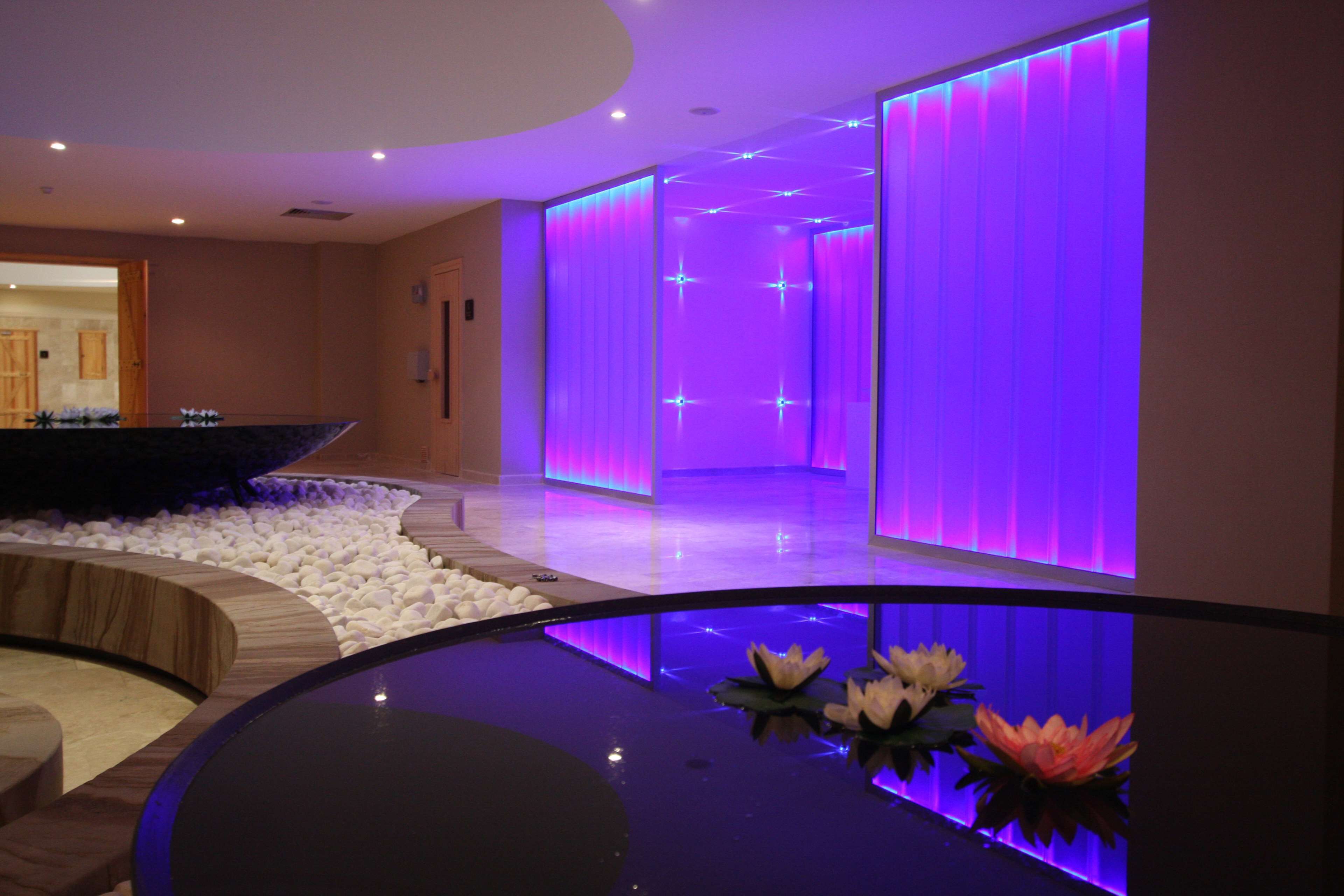 A modern spa area with a water feature, a reception desk, and a reception area with purple lighting.