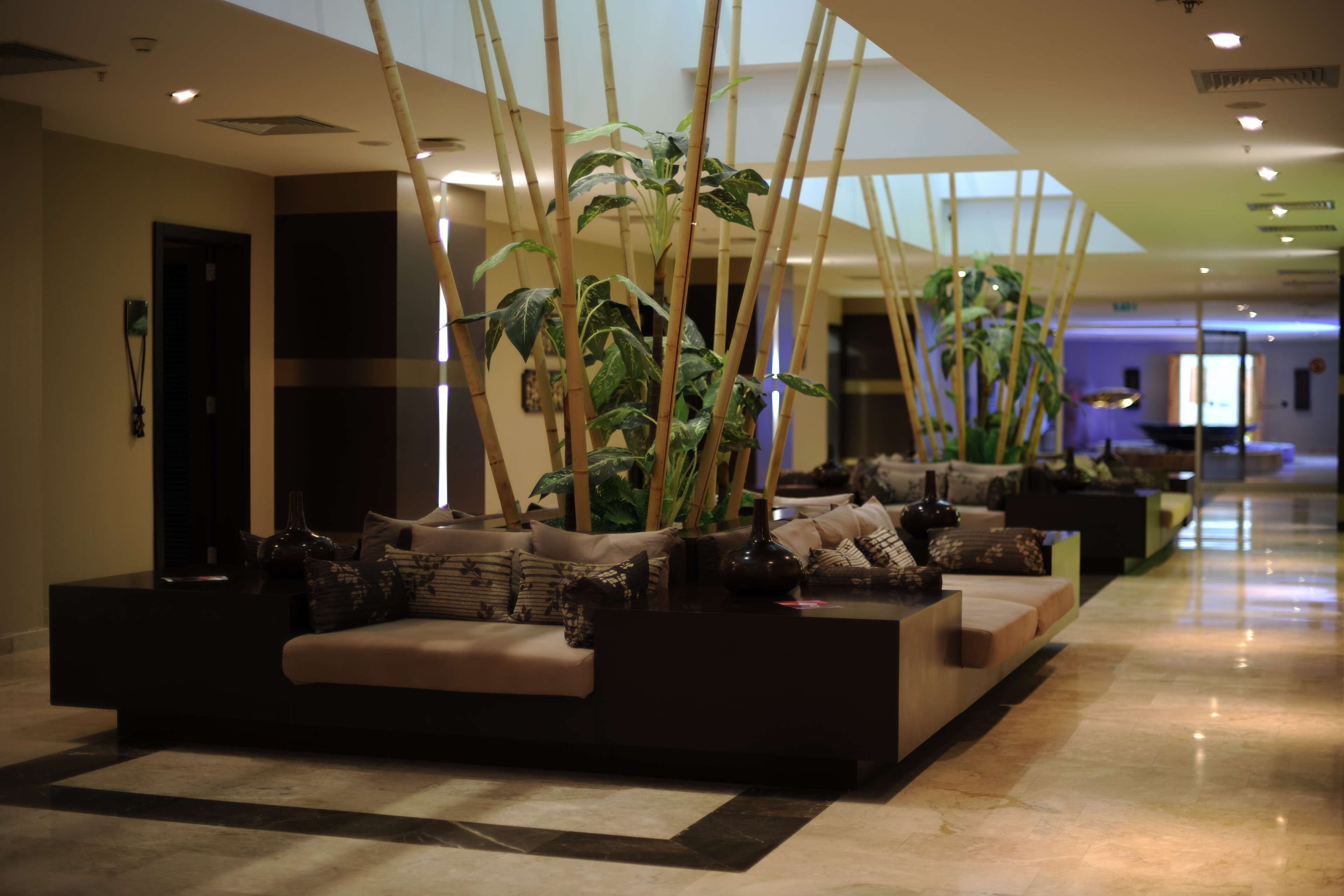A modern lobby with a sofa area, bamboo plants, and a reception desk.