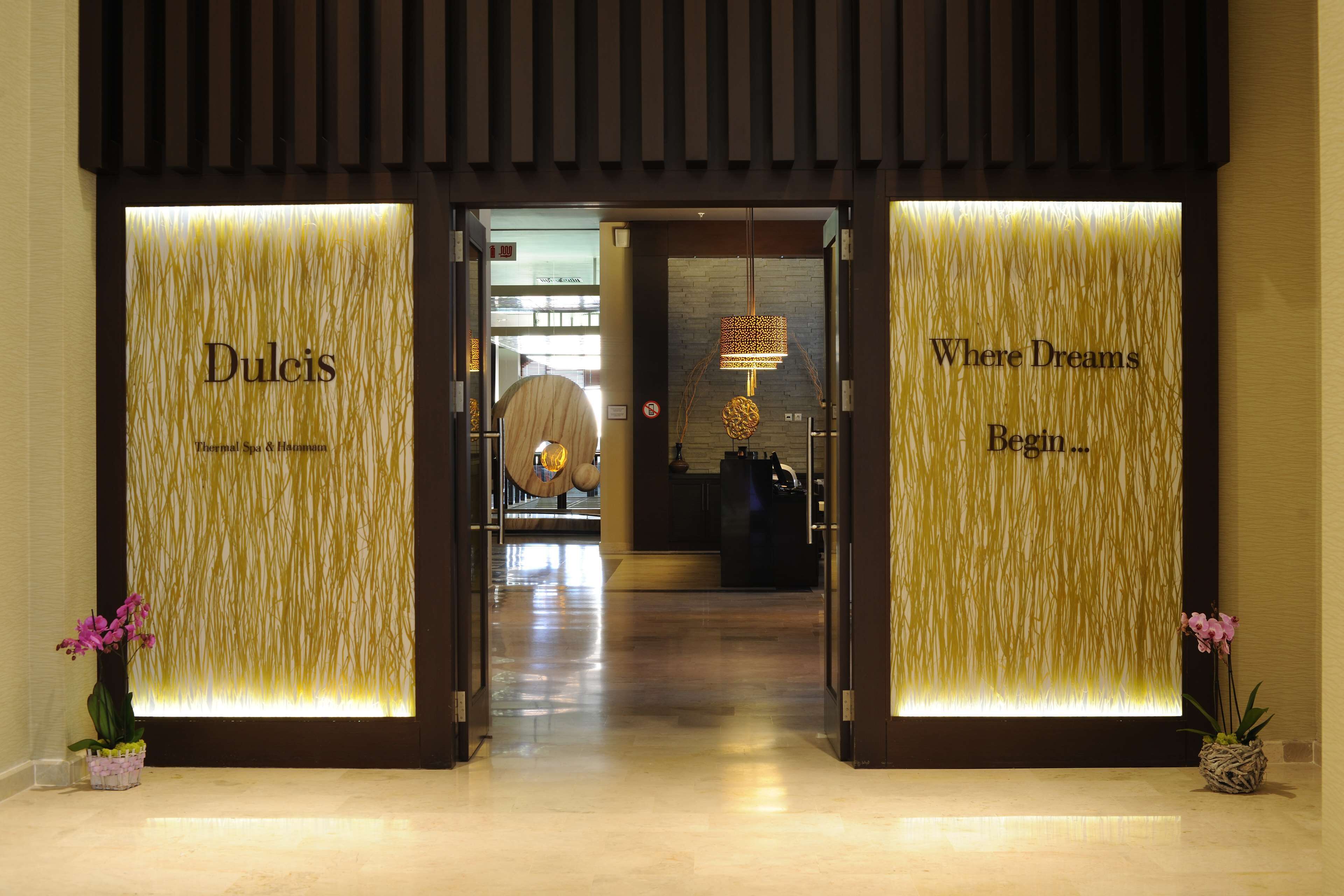 Entrada de hotel con dos letreros iluminados que dicen "Dulcis" y "Where Dreams Begin".