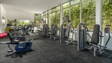 Ett gym med olika träningsmaskiner, stora fönster och ett svart gummigolv.