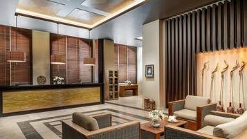 A modern lobby with wicker furniture, a reception desk, and decorative wall panels.