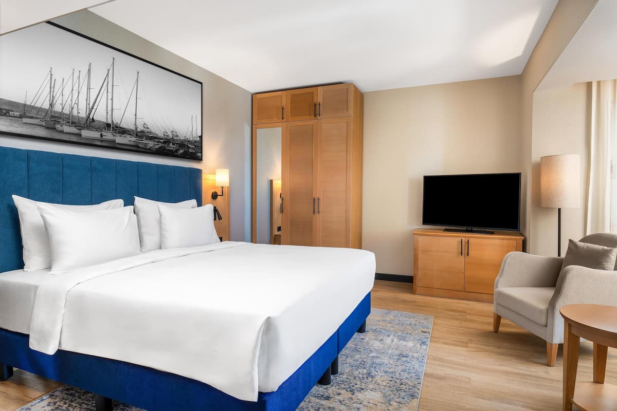Ein Hotelzimmer mit einem großen Bett, einem Fernseher, einem Kleiderschrank und einer Sitzecke.
