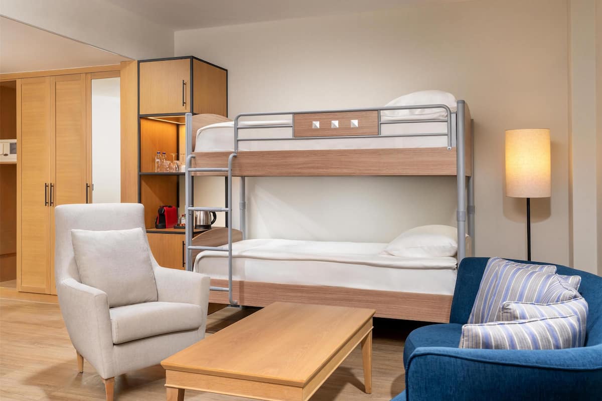 Ein Stockbett mit Schreibtisch und Stuhl, eine Couch und ein Kleiderschrank.