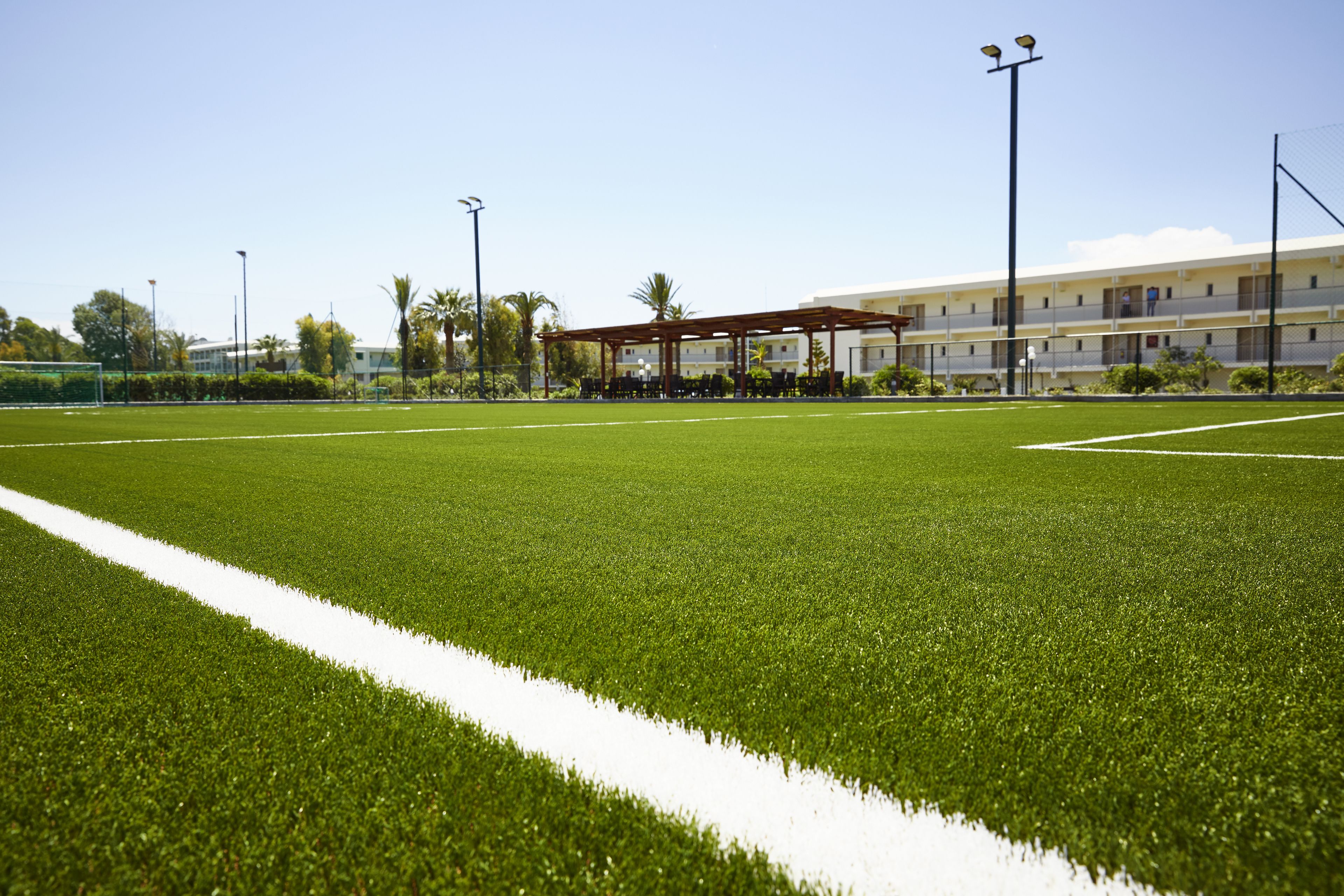 A well-maintained sports field with a pavilion and a building in the background.