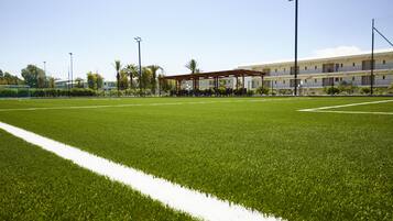 A well-maintained sports field with a pavilion and a building in the background.