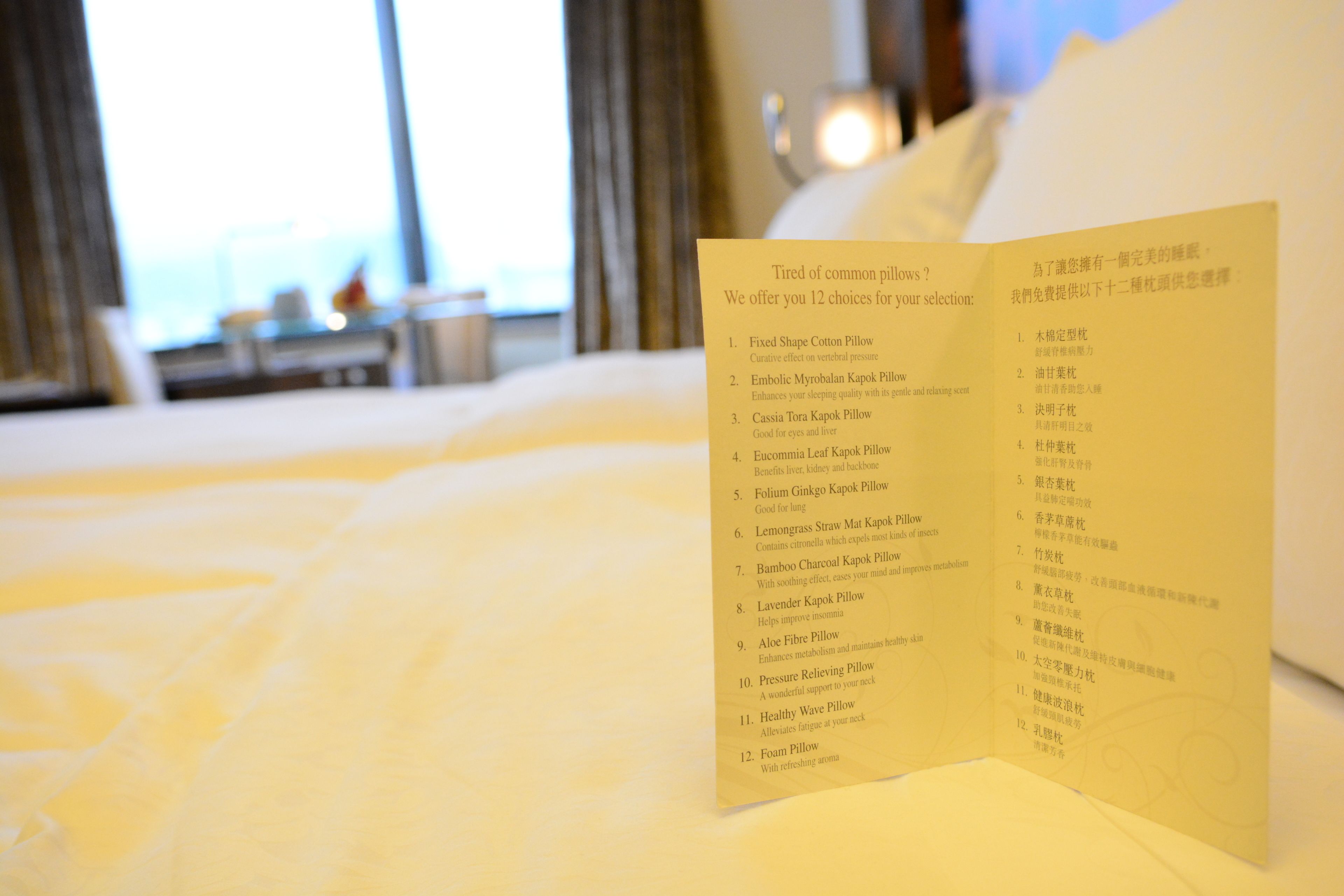 A hotel room with a neatly made bed and a menu listing 12 pillow choices.