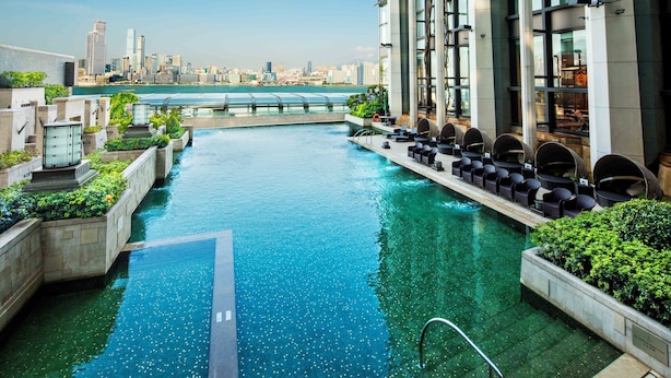 A rooftop infinity pool with a city skyline view, surrounded by lounge chairs and greenery. - Harbour Grand Hong Kong (Hong Kong)
