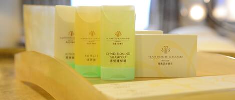 A set of toiletries including lotion, bath gel, and shampoo, along with a hotel brochure, all placed on a tray.