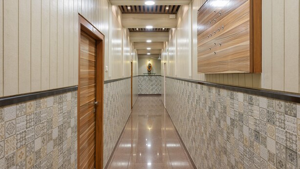 A corridor with patterned tiles, wooden paneling, and a tiled floor. - Hotel Royal Castle (Mumbai)