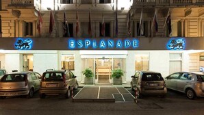 A hotel entrance with the name "ESPLANADE" and a lion logo. There are cars parked in front, and flags are visible above the entrance. - Hotel Esplanade (Pescara)