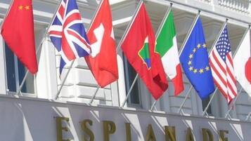 The exterior of a building with the sign 'ESPLANADE' and multiple national flags displayed outside.