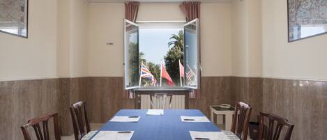 Un salón de conferencias con una mesa grande, sillas y un ventanal con banderas.