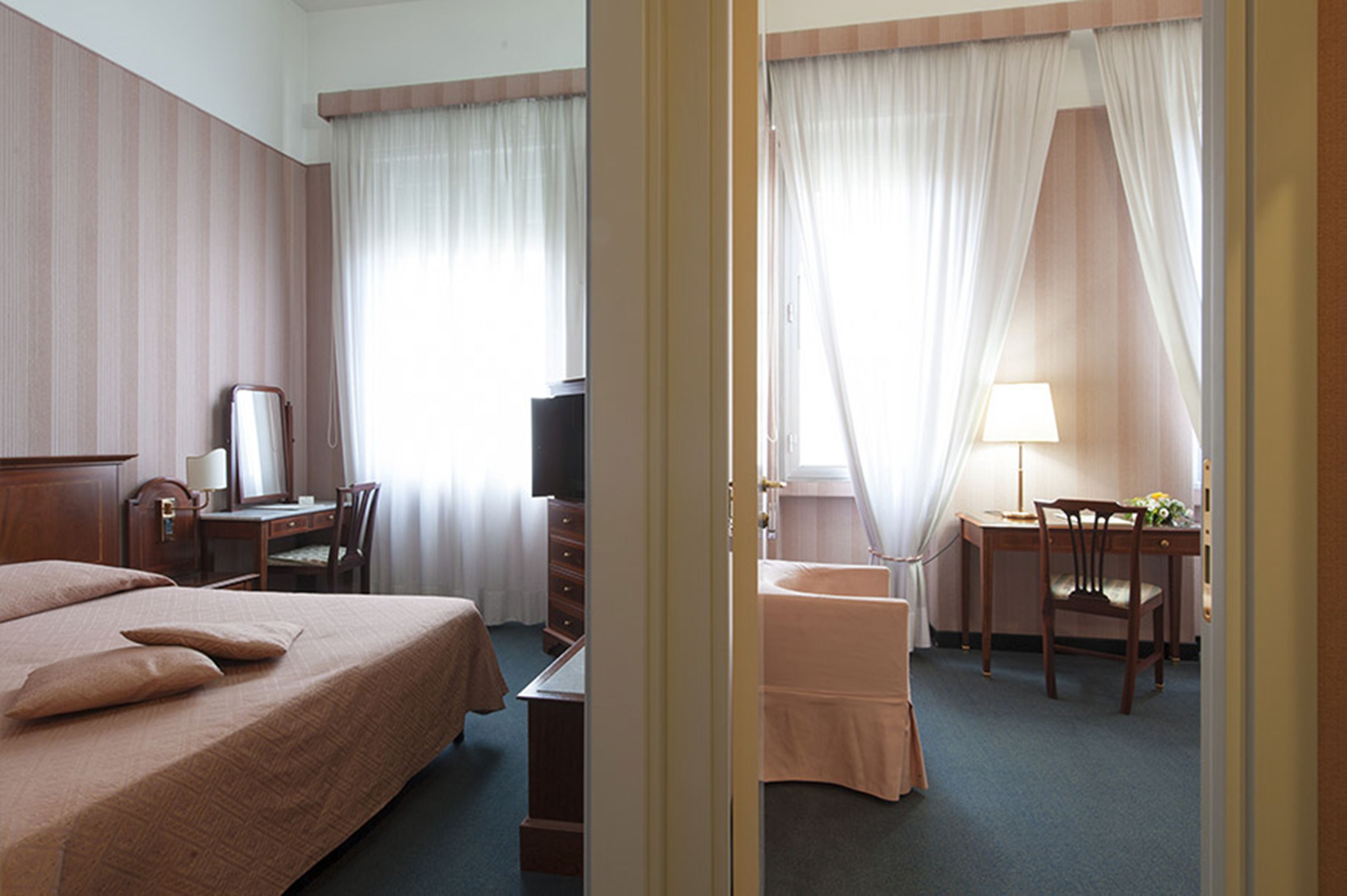 Une chambre d’hôtel équipée d’un lit, d’un bureau, d’une chaise, d’une télévision et d’une fenêtre avec des rideaux.