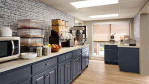 A modern kitchen with a microwave, coffee maker, and a brick-patterned backsplash.