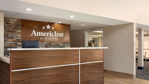 A reception desk with a wooden finish and a sign that reads "AmericInn by Wyndham".