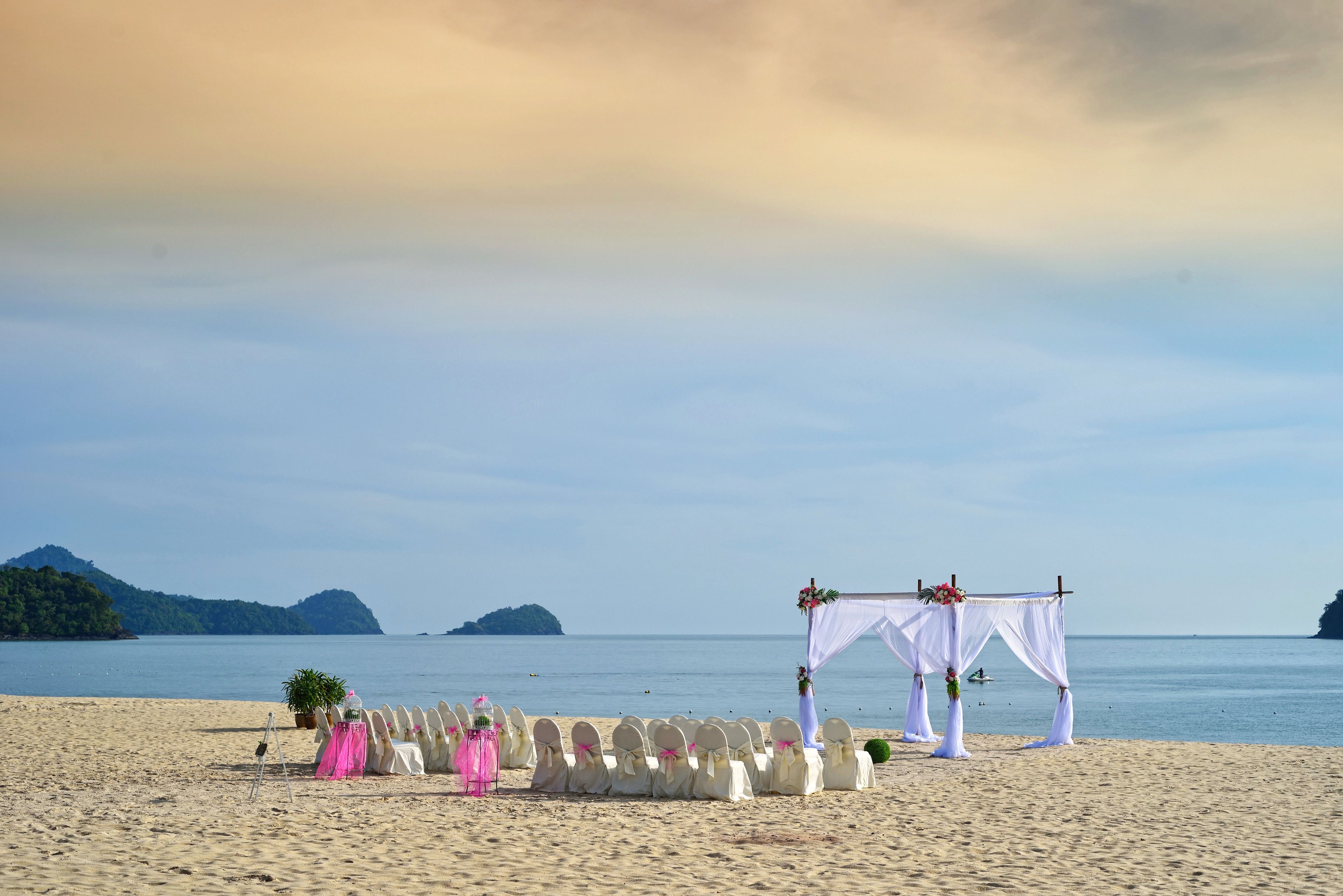 A beach wedding setup with a canopy and chairs arranged for guests.