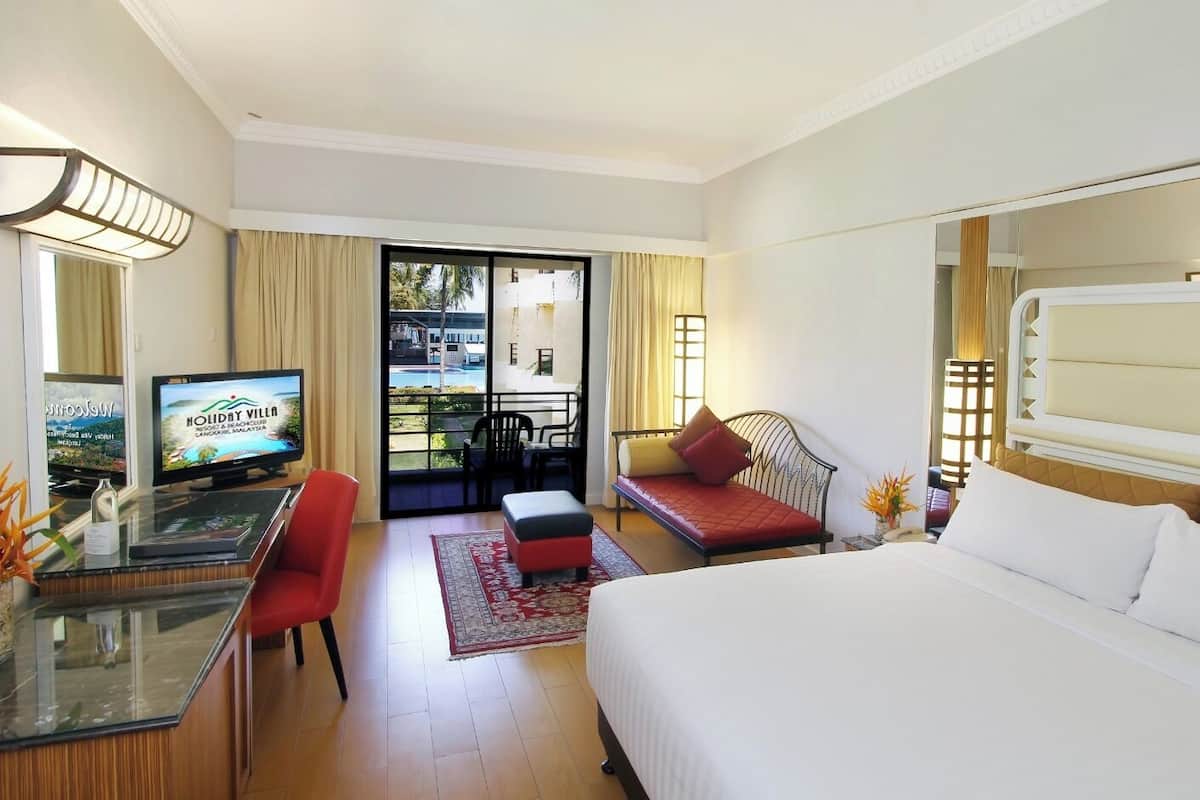 Habitació d'hotel amb un llit, un escriptori amb un ordinador, una televisió i vista a la piscina.