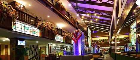 A spacious lobby with multiple seating areas, a staircase, and a television screen.