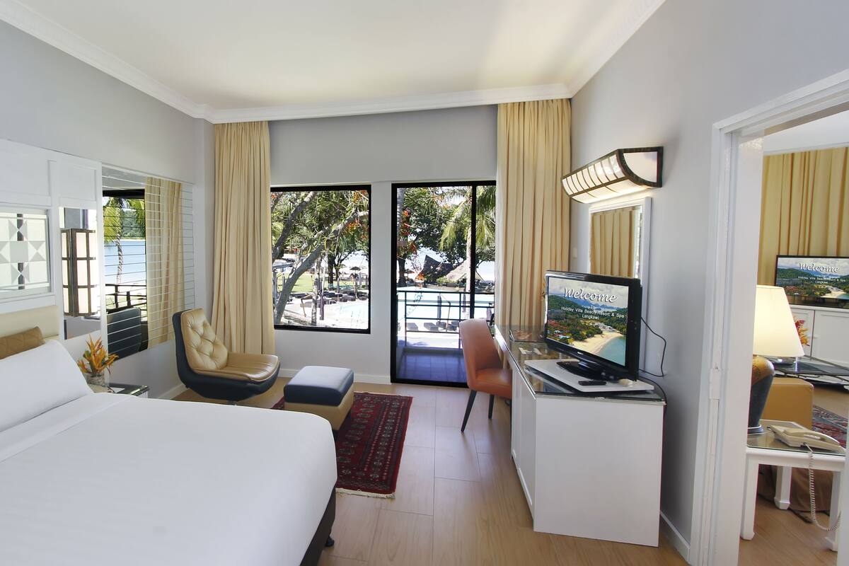 Une chambre d’hôtel avec un lit, un bureau avec une télévision, une chaise et une vue sur l’extérieur.