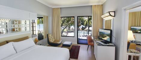A hotel room with a bed, a desk with a television, a chair, and a view of the outdoors.