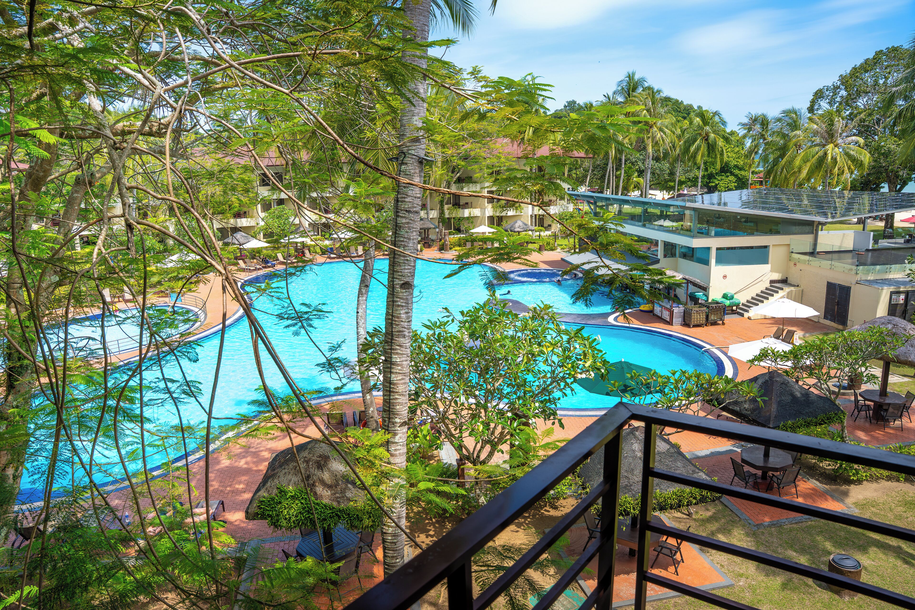 A pool area with multiple swimming pools, lounge chairs, and palm trees.