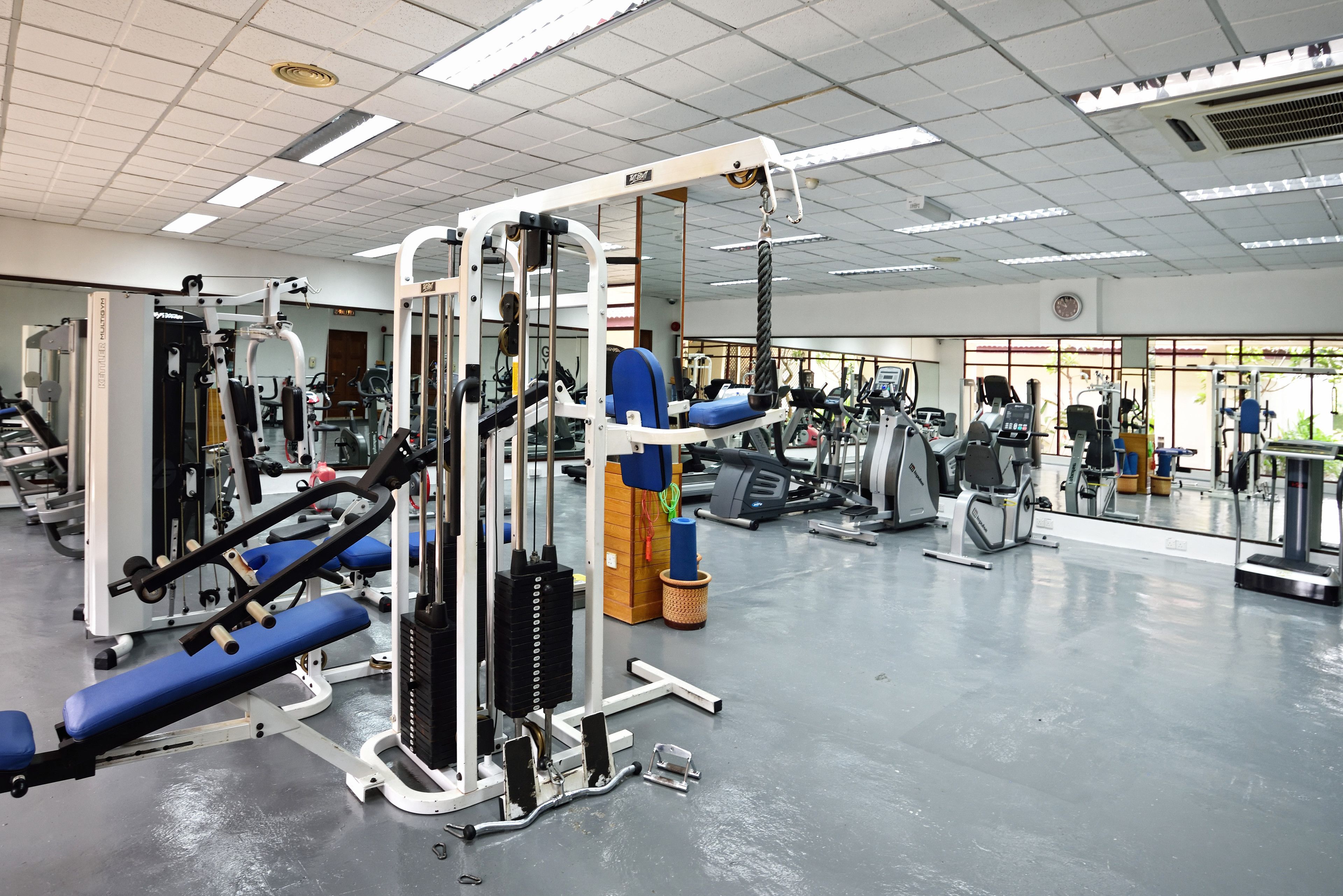 A gym with various exercise machines, mirrors, and a clean, well-lit space.