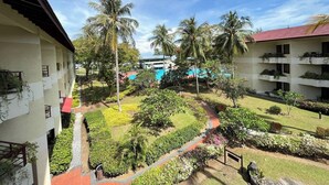 Une cour d’hôtel avec une piscine, des palmiers et un jardin bien entretenu.