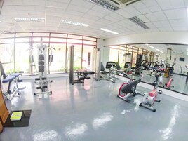 A gym with various exercise equipment, large windows, and a mirrored wall.