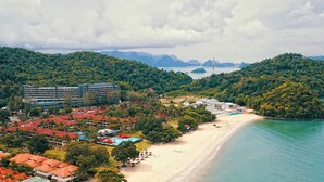 Une station balnéaire dotée d’une plage, d’une piscine et d’une végétation luxuriante.