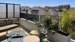 Un balcon avec vue sur la ville, une table avec des boissons et des sièges en plein air.
