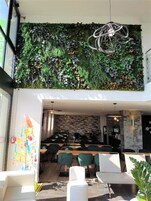 Um interior moderno com uma parede verde, área de estar e uma escadaria que leva aos andares superiores.