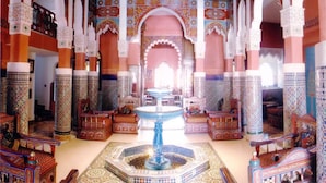 An ornate interior with a central fountain, high arches, and detailed tile work.