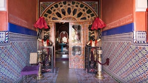 A hallway with intricate tile work, a central archway, and two statues on either side.