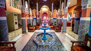 An ornate interior with a central fountain, high ceilings, and intricate tile work.
