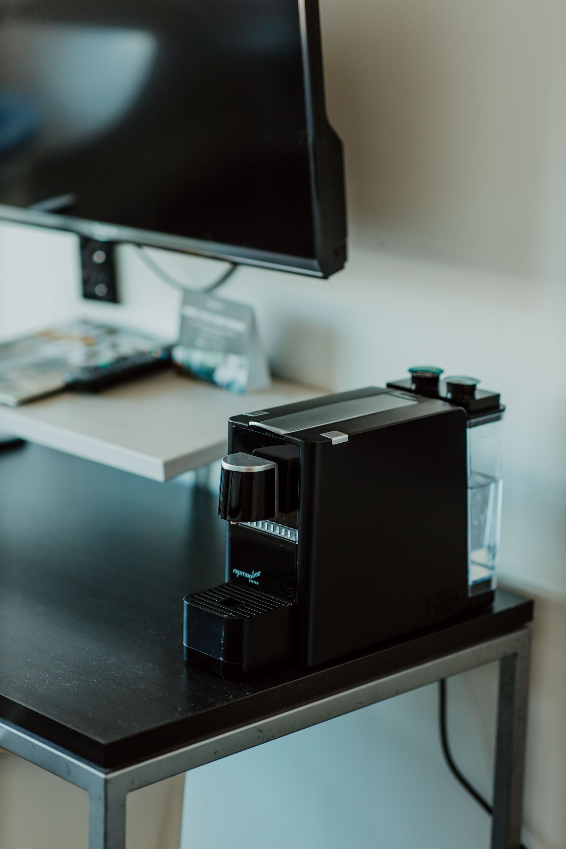 A coffee machine on a desk with a computer monitor and a keyboard.
