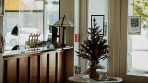 A reception desk with a small Christmas tree, a lamp, and a framed sign. - Quest Napier Serviced Apartment (Napier)