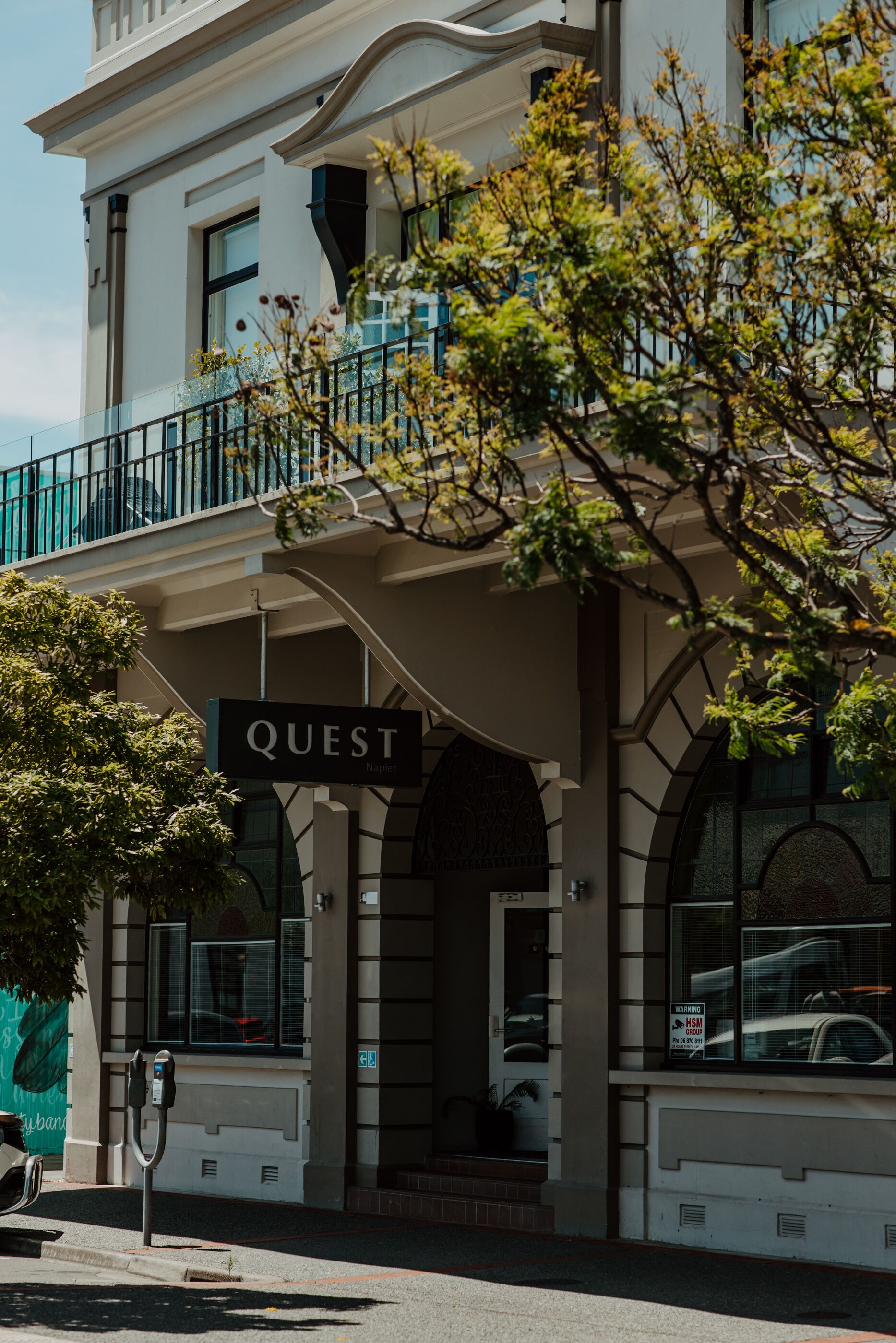 A building with a sign reading "QUEST" and a parking meter in front.