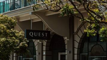 A building with a sign reading "QUEST" and a parking meter in front.