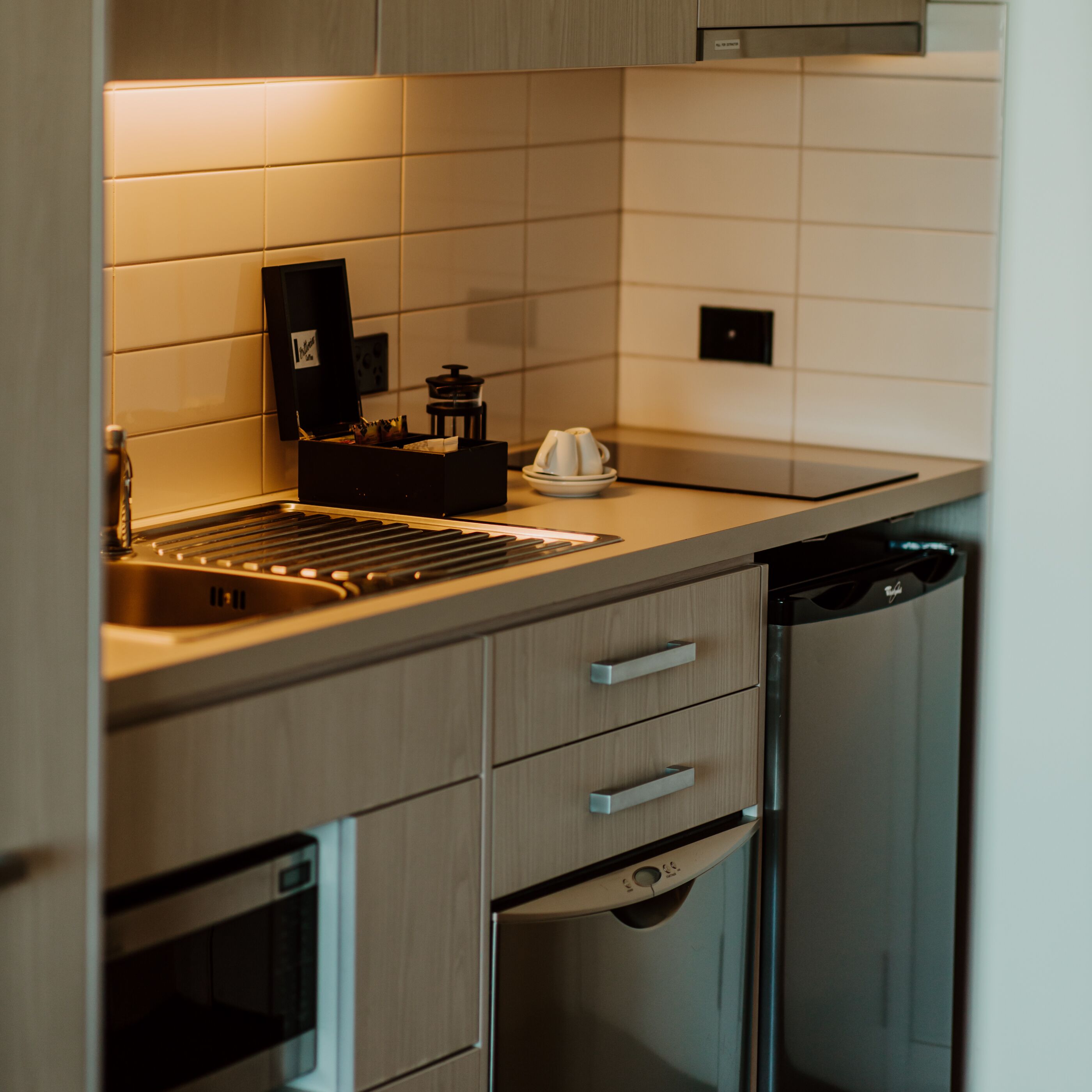 A modern kitchen with a stainless steel dishwasher, a coffee machine, and a sink.